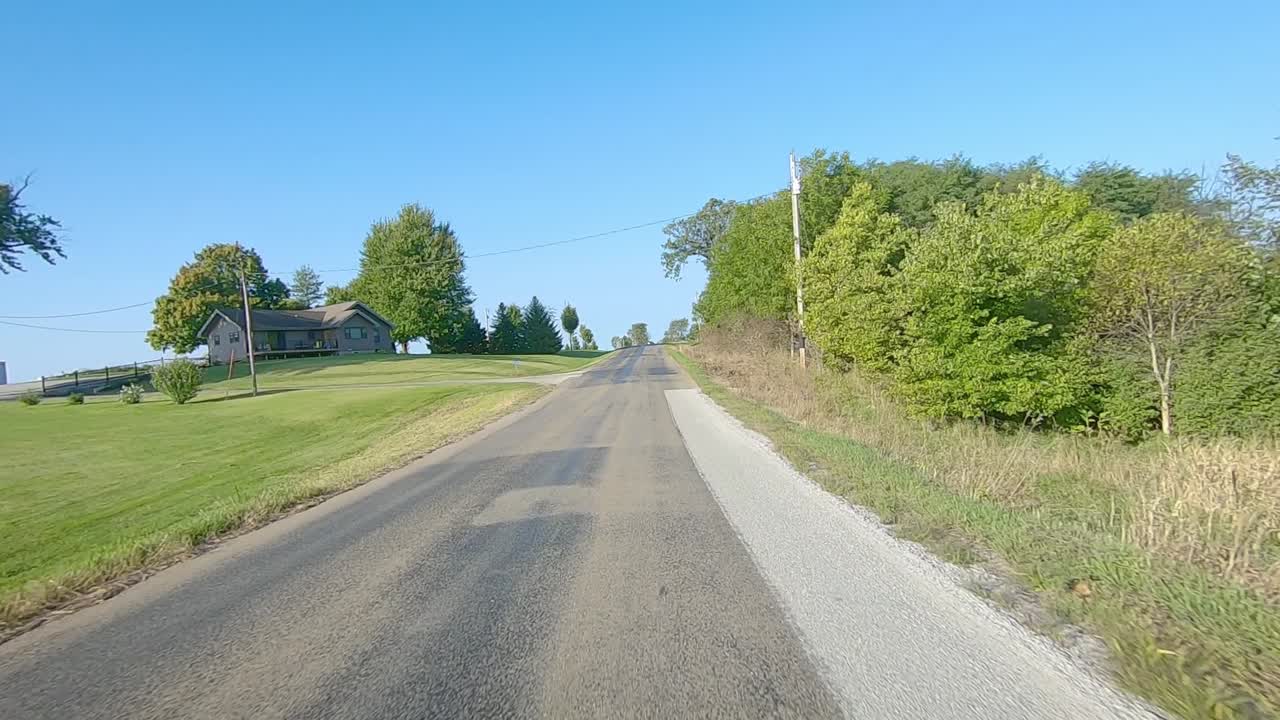 미국 아이오와주 칼로나 근처의 화창한 초가을날 시골 아이오와에 있는 성숙한 들판과 큰 농장 구내를 지나 중앙선이 없는 카운티 도로에서 pov 운전