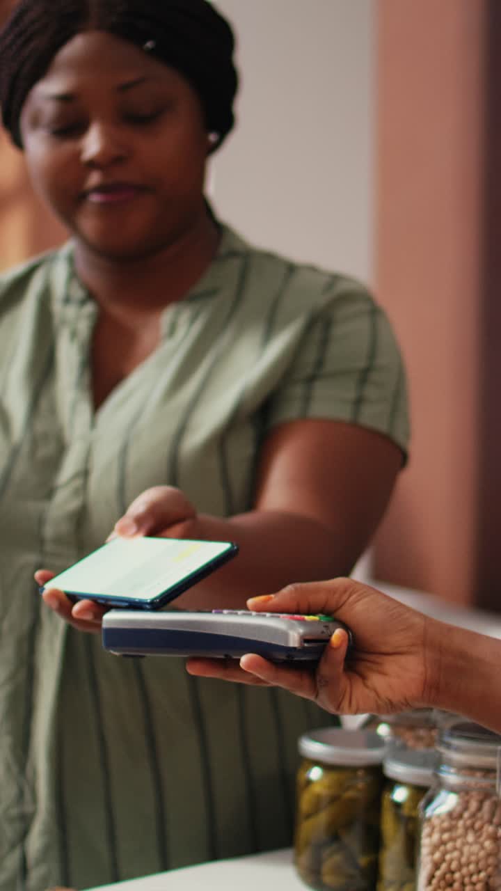 Video verticale: donna che acquista cibo tramite pagamento NFC al terminale POS