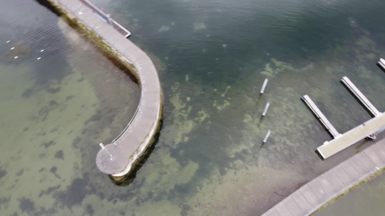 vista aérea circular del lago constance que muestra sus pequeños muelles rodeados de sus aguas tranquilas en el medio de los alpes, bregenz en austria