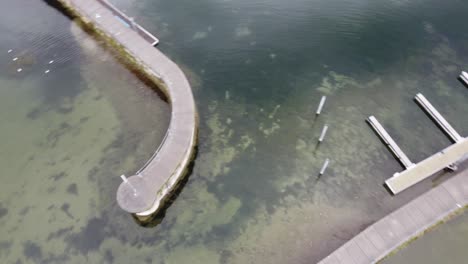 Circular-aerial-view-of-Lake-Constance-showing-its-small-piers-surrounded-by-its-calm-waters-in-the-middle-of-the-Alps,-Bregenz-in-Austria