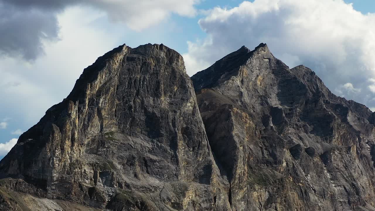 alejamiento aéreo y orbitando alrededor de las cumbres de la montaña sukakpak contra nubes blancas en verano alaska