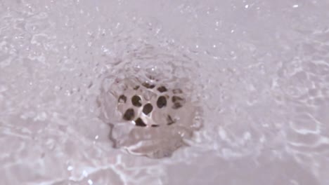 close-up underwater view of the drain in a bath tub with water pouring out of the faucet.