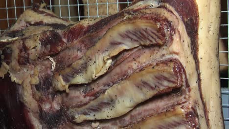 dry ageing marinated pork ribs hanging in cellar, closeup tilt shot