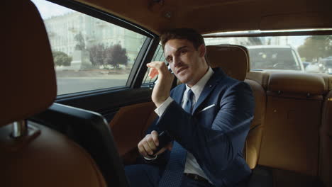 joyful businessman dancing with mobile phone in interior of business car.