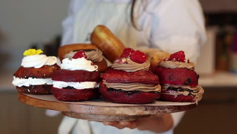 crop woman with berliners on tray in bakery