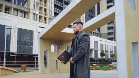 male in suit working outside on laptop. video with a young businessman in a street.
