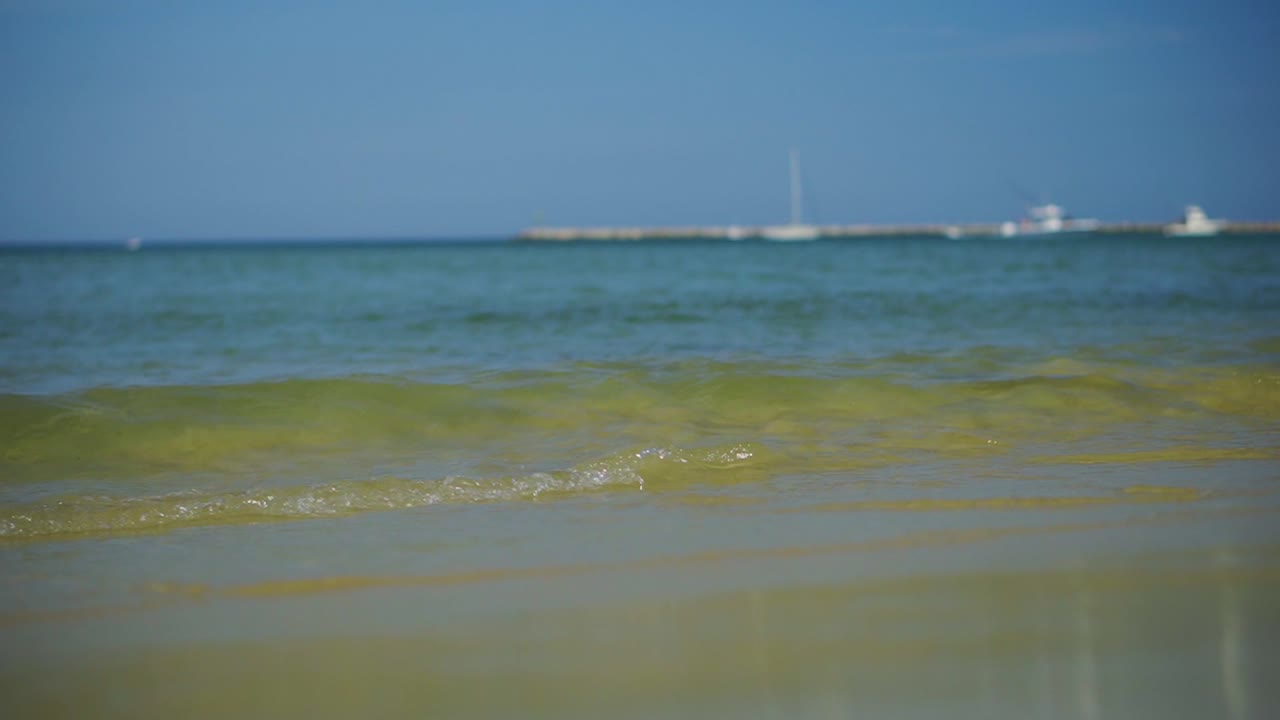 여름철 열대 해변에서 맑은 청록색 물로 부서지는 파도