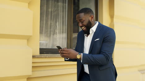 Lächelnder-Afro-Geschäftsmann,-Der-Draußen-Eine-SMS-Schreibt.-Afro-Mann-Liest-Nachrichten