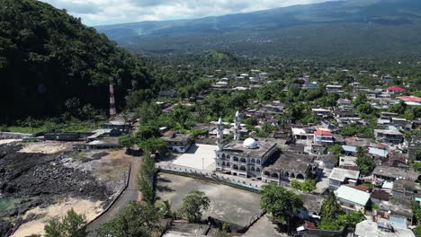 aerial shot of coastal town with a mosque and rocky shoreline with lush green trees.
