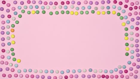 creative frame pastel pink background with rainbow candies. stop motion flat lay