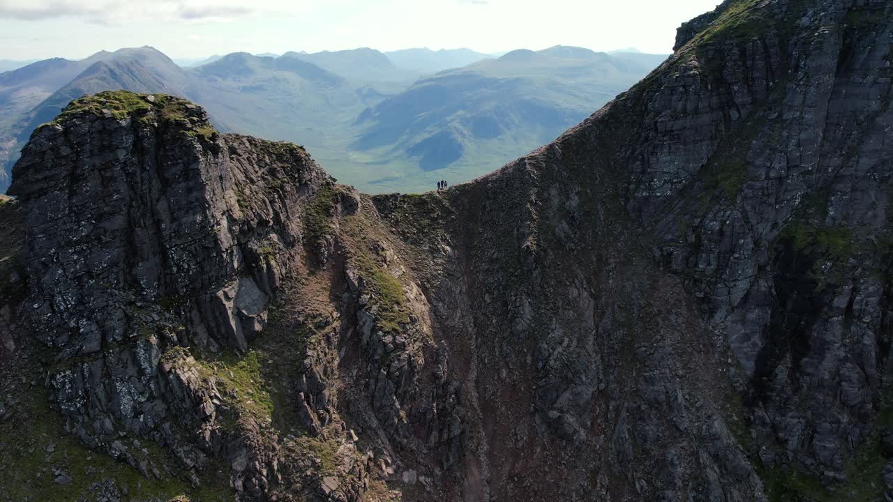 tres personas caminando sobre el hermoso acantilado de piedra en un teallach en el reino unido en un día nublado