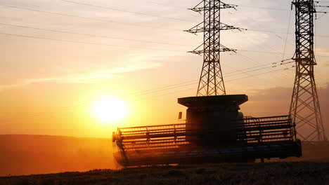harvesting at sunset in rural fields. a combine harvester works through fields as the sun sets, creating a beautiful silhouette against the vibrant sky