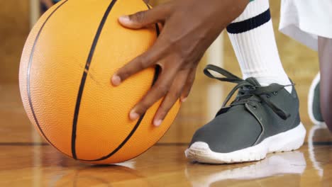 high school kid tying shoe lace in basketball court