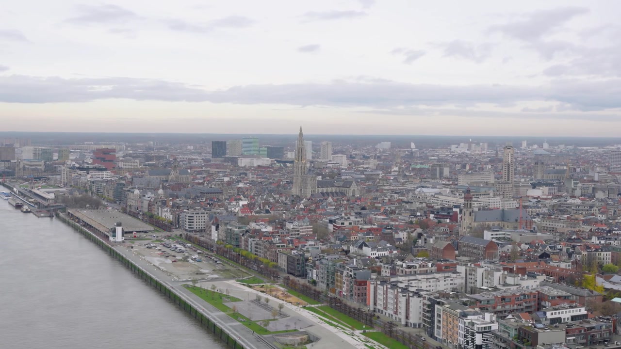 Omfattende dronekredsløb omkring Antwerpen Katedral, der afslører byens skyline, Schelde-floden og bylandskabet under en overskyet himmel