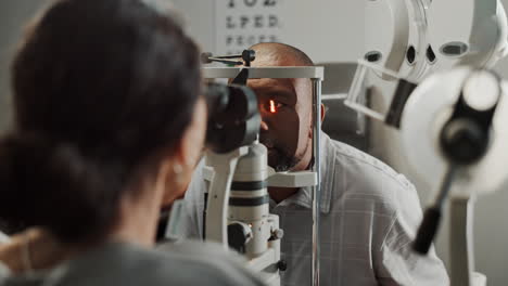 optometrist examining a patient's eye with a red light