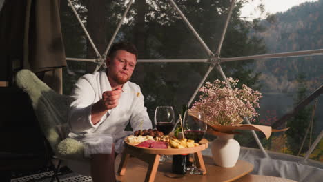 hombre disfrutando de una comida gourmet en una cúpula de glamping