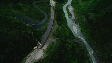 Mountain-highway-beside-a-river-in-a-valley