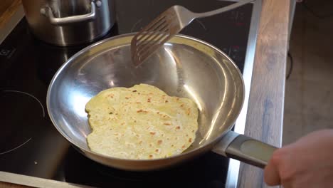 frying a slice of tortilla dough in a frying pan