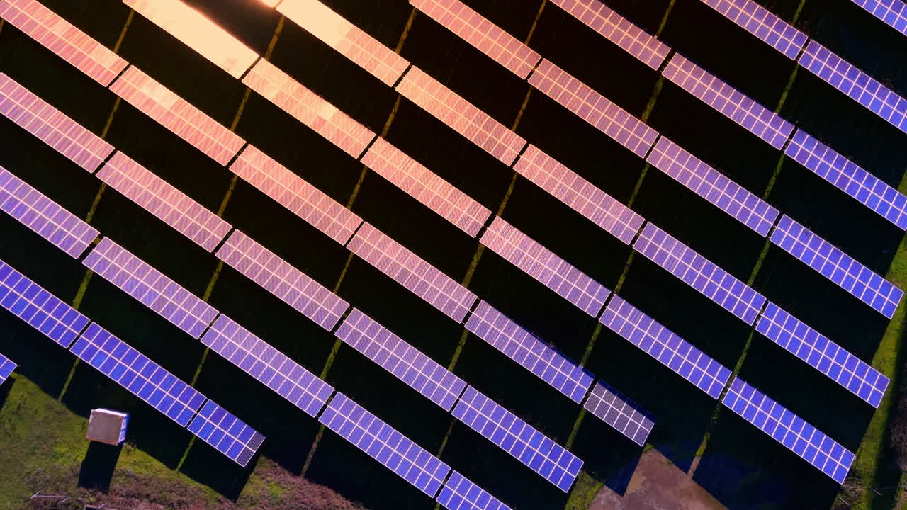 Composizione diagonale di moduli fotovoltaici al tramonto con la luce solare intensa che si riflette sulla superficie di vetro. Vista aerea ravvicinata di pannelli solari con raggi solari.