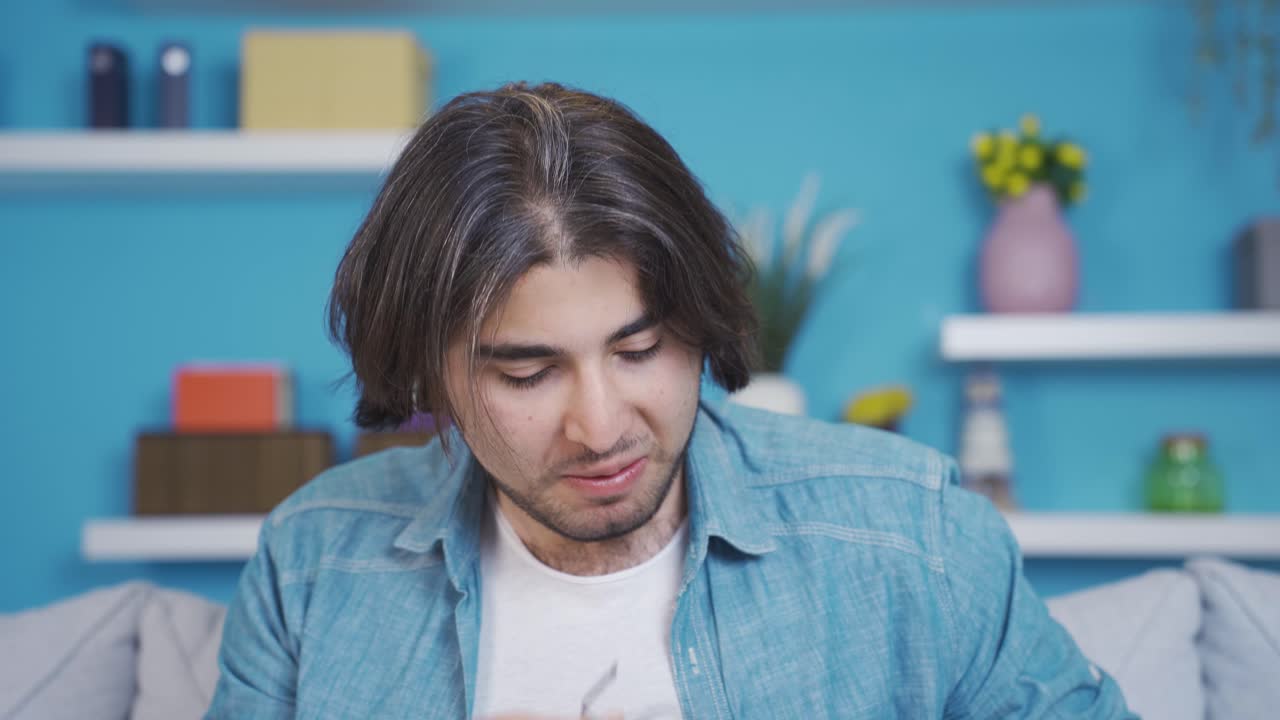 재미있고 유쾌한 젊은이가 안경을  ⁇ 고 카메라를 쳐다보고 있습니다.