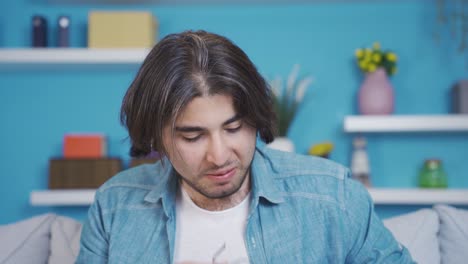 un joven divertido y alegre se está limpiando las gafas y mirando a la cámara.