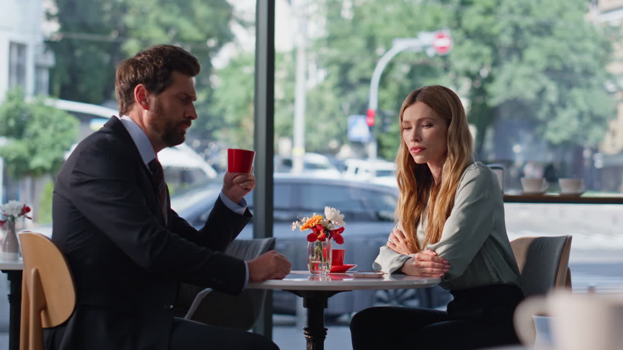 Offended girlfriend sitting cafe with boyfriend drinking coffee. Tensed couple