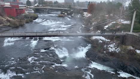 Vista-Aérea-De-Un-Puente-Peatonal-Sobre-Las-Cataratas-De-Spokane-Durante-Un-Frío-Día-De-Invierno