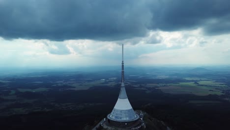 jested tower during a part clouded day with liberec town in the distance, drone orbiting, descending and pan up, 4k or uhd, 30fps