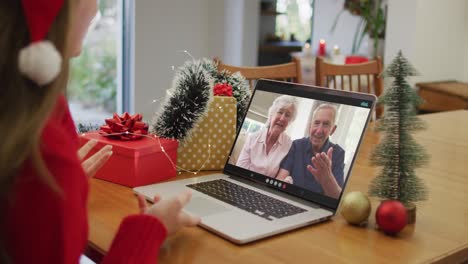 Happy-caucasian-woman-on-video-call-with-grandparents-at-christmas-time