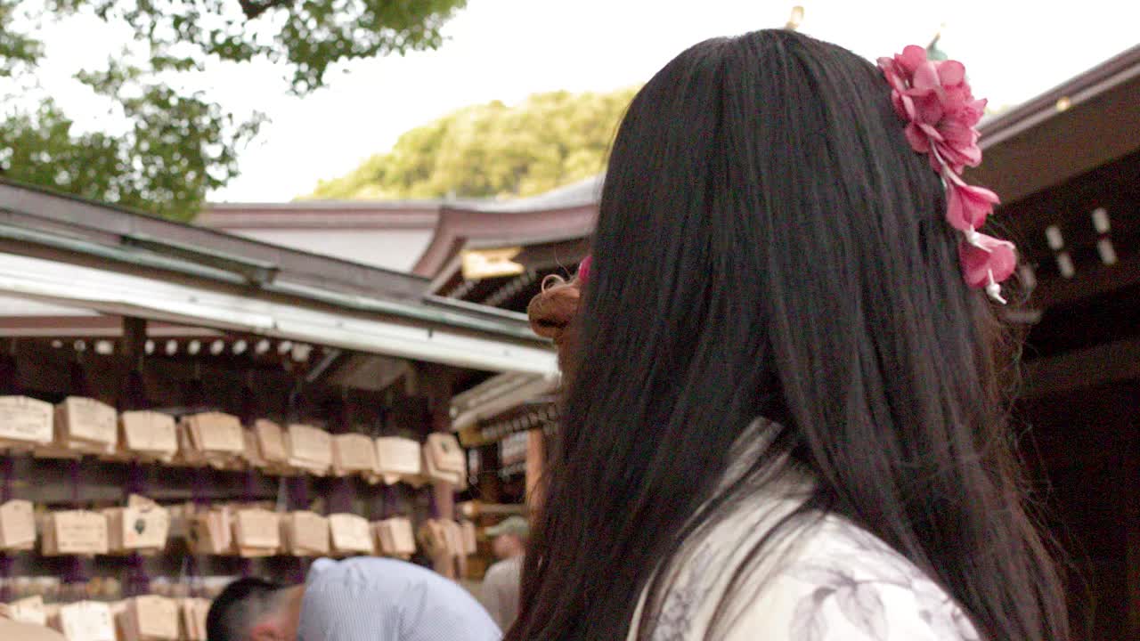 日本の神社で、木製の絵馬のそばを通り過ぎる伝統的な着物を着た2人の女性