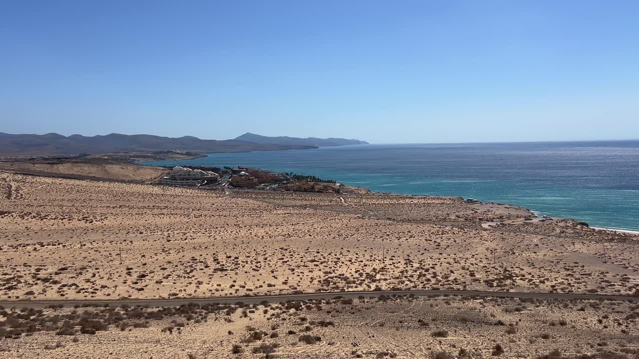 High-angle scenic view of the arid southern coastline of Fuerteventura, showing volcanic terrain meeting the deep blue Atlantic Ocean. Canary Islands, Spain