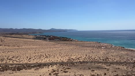 high-angle scenic view of the arid southern coastline of fuerteventura, showing volcanic terrain meeting the deep blue atlantic ocean. canary islands, spain