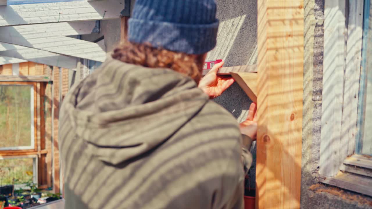 Man At Work In A Greenhouse - Building Shelves For Plants
