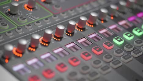 4k close up of professional young woman adjusting audio levels on studio mixer console with colorful dials