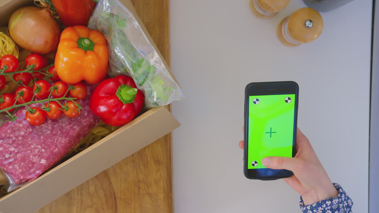 신선한 재료를 가진 부에서 온라인 레시피를 찾는 여성의 오버헤드  - 녹색 화면 휴대 전화 - 느린 동작으로 촬영