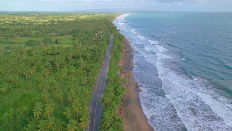 Paisaje-Idílico-De-Playa-Y-Carretera-Con-Vehículos-Que-Viajan-En-Nagua,-República-Dominicana---Toma-Aérea-De-Drones