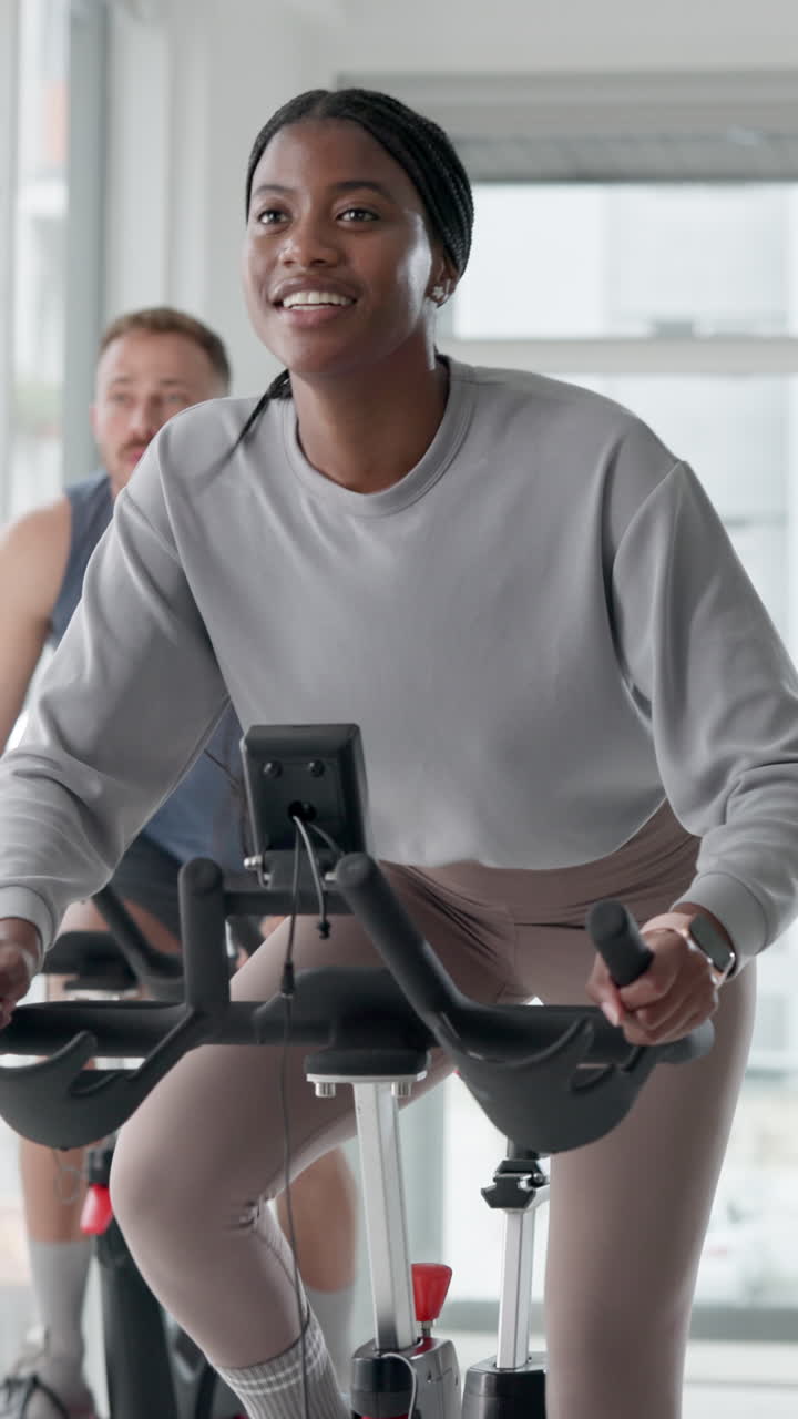 Giovane donna nera che si allena su una cyclette in una palestra moderna.