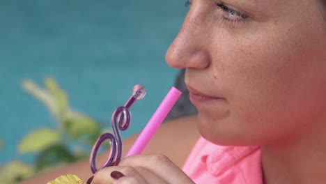 blue water ripples behind young woman drinking cocktail