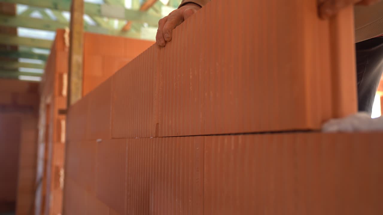 Worker aligns ceramic blocks while constructing wall in unfinished house