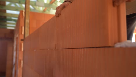 worker aligns ceramic blocks while constructing wall in unfinished house