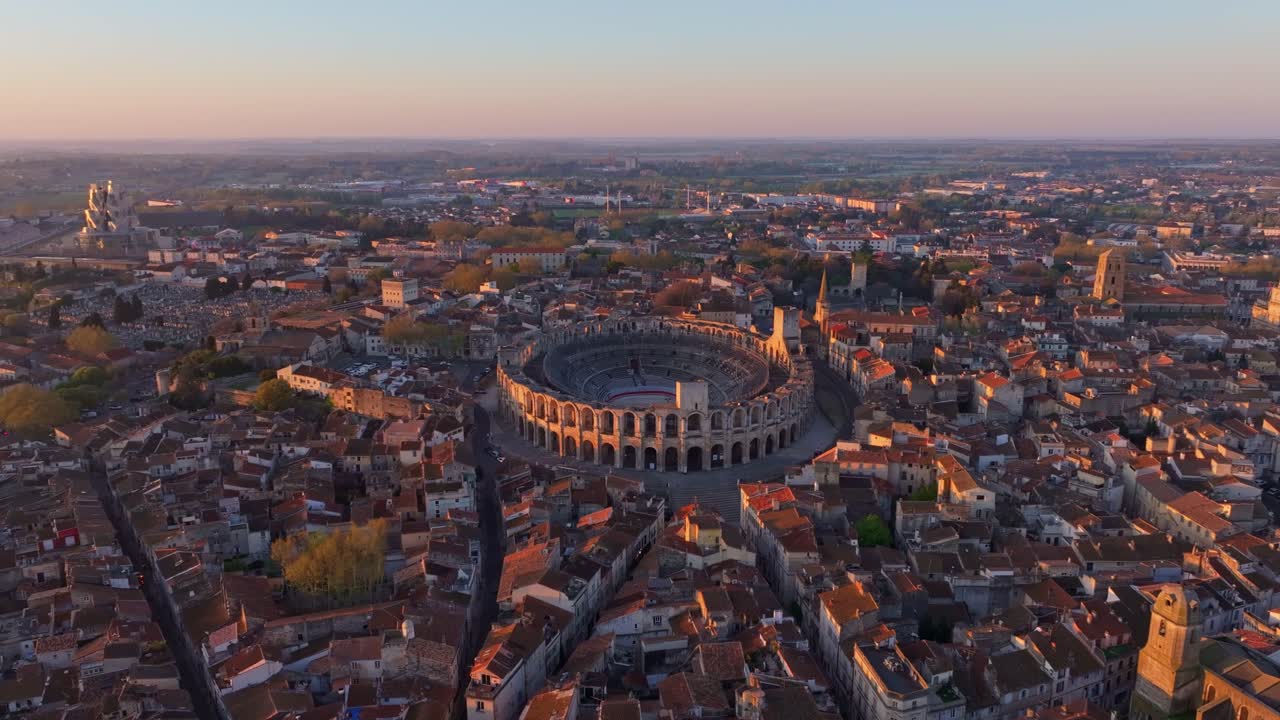L'alba soffusa rivela Arles dall'alto con un monumento romano