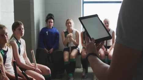 entrenador de hockey usando una tableta digital en el vestuario