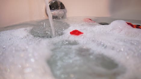 Bath-tub-running-full-of-water-with-foam-and-rose-petals