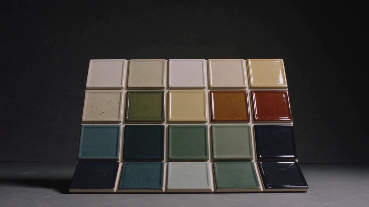Shifting bottom-right tile causing separation from 5x4 glazed grid on gray board in studio, gloss