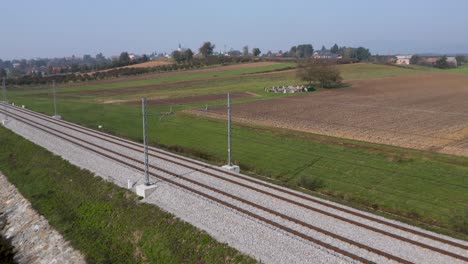 aerial view of train tracks spanning through rural farmland in the slovenian countryside near the village of cresnjevec