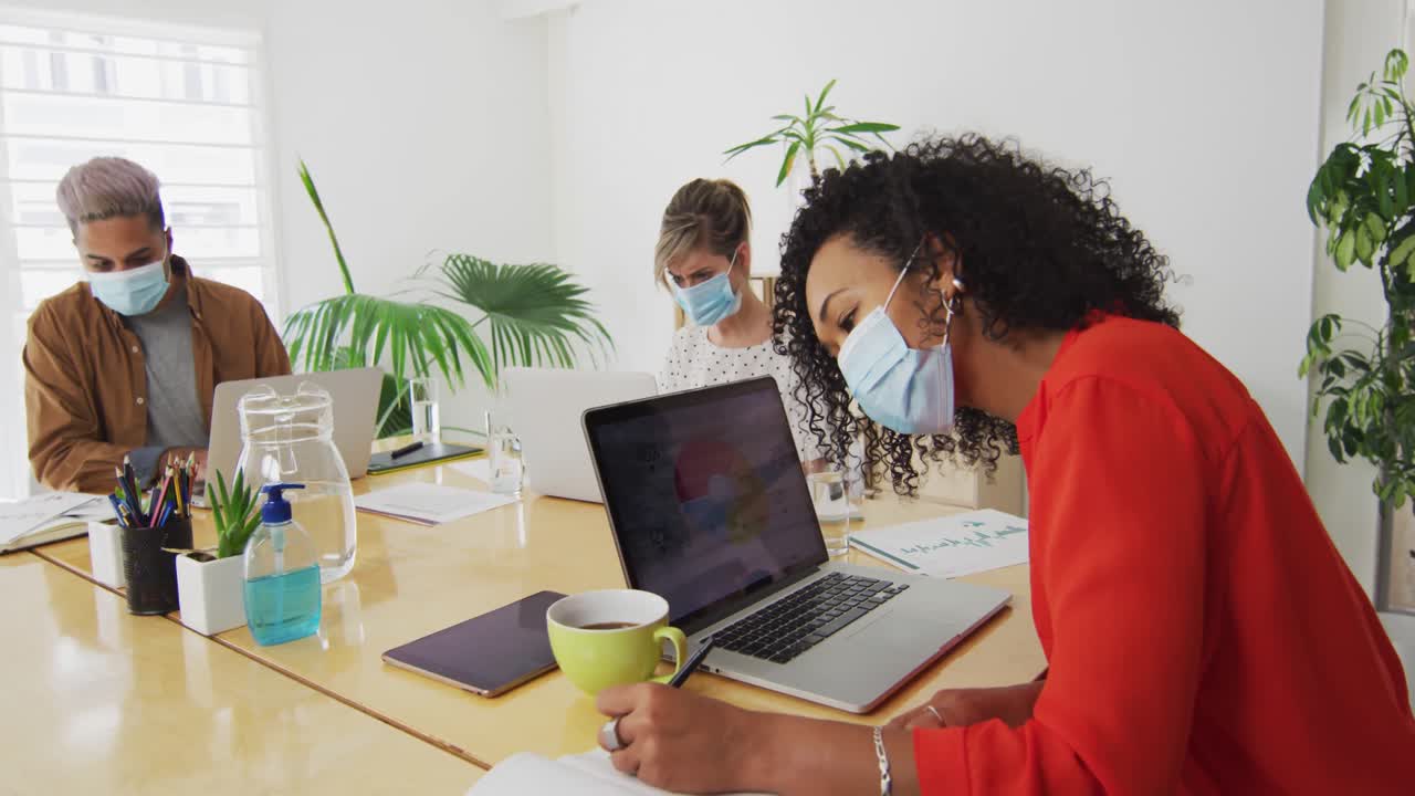 Woman wearing face mask taking notes in office