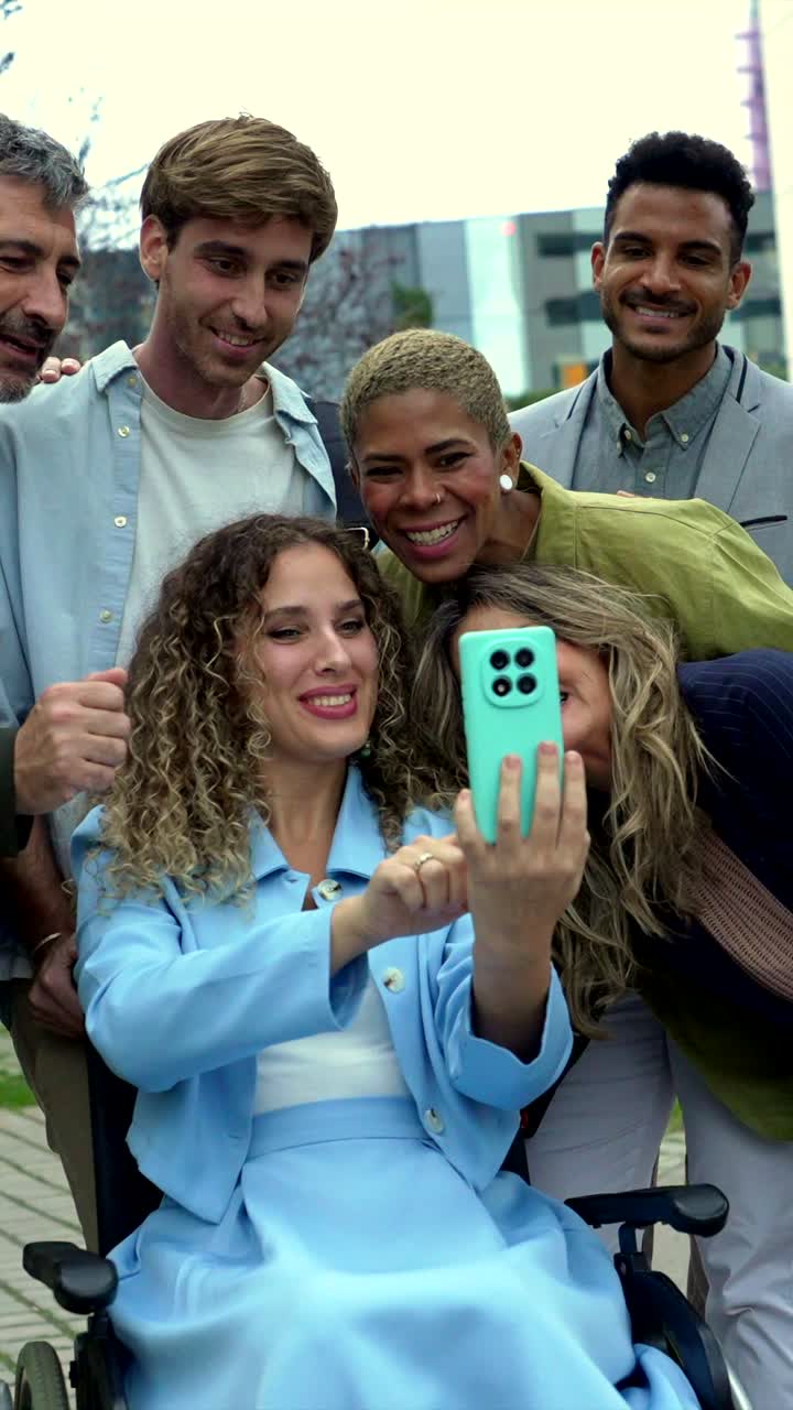 Gruppo di persone diverse che fanno un selfie con una donna in sedia a rotelle
