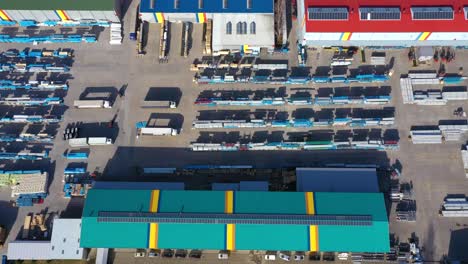 trucks with semi-trailers stand on the parking lot of the logistics park with loading hub and wait for load and unload goods at warehouse ramps at sunset