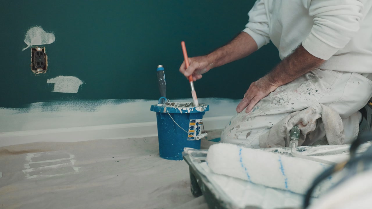 Painter Dips Brush Into Paint Bucket