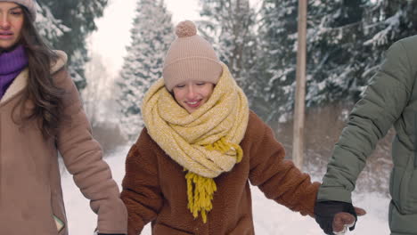 close up view of parents and daughter dressed in winter clothes walking in snowy forest